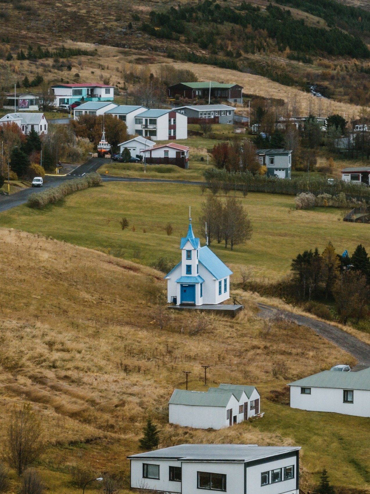 Tiny Church surrounded by village houses and dry hillside grass