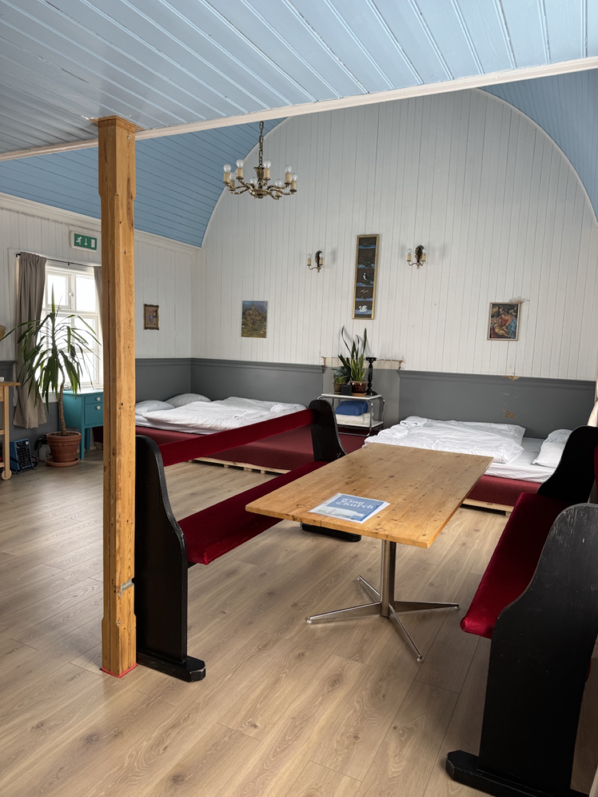 Inside Tiny Church with red benches, beds, table and high blue ceiling